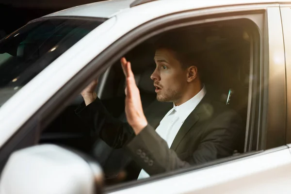 Młody biznesmen wygląda zdumiony z rękami w górze koło kierownicy jest zatrzymany przez policję podczas jazdy samochodem, koncepcja bezpieczeństwa jazdy — Zdjęcie stockowe