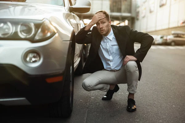 young handsome businessman looks nervous just had car crush in the middle of the road , unexpectable vehicle trouble