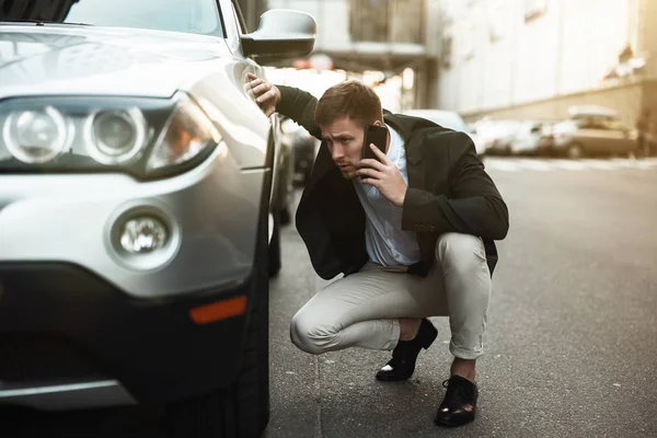 Joven hombre de negocios guapo se ve nervioso acaba de tener aplastamiento del coche en el medio de la carretera llamando a la asistencia de la estación de servicio, problemas inesperados vehículo — Foto de Stock