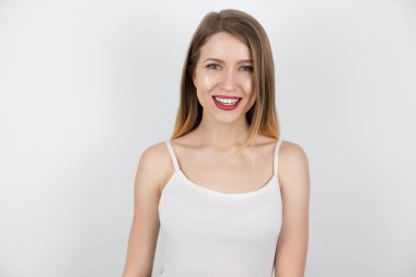 İzole edilmiş beyaz arka plan, sağlık ve güzellik anlayışı ile mutlu ve tatmin olmuş genç sarışın kadının portresi.