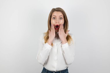 İzole edilmiş beyaz arka planda duran genç sarışın kadın şaşırmış görünüyor, saf güzellik kavramı.