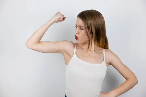 Mooie sterke blonde vrouw demonstreert haar arm biceps staan op geïsoleerde witte achtergrond, gezondheidszorg en sport concept — Stockfoto