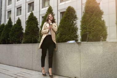 Genç ve güzel bir ofis çalışanı telefon görüşmesi yapıyor. Laptopunda çalışıyor. Öğle arasında sokakta kahve içiyor..