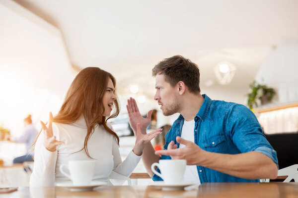 young couple beautiful woman and handsome man fighting, having argument while drinking coffee in cafe during lunch time break, problematic relationships concept.
