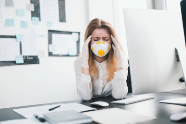 Tıbbi koruma maskesi ve eldiven takan genç sarışın kadın yönetici, Covid-19 epidemi, viroloji konsepti sırasında ofiste çalışırken rahatsız ve endişeli görünüyor..