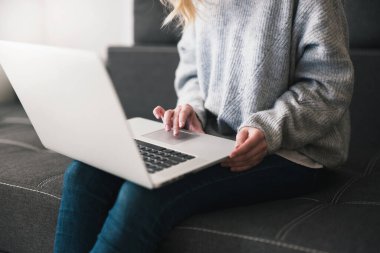 Kadın yönetici kanepede oturup dizüstü bilgisayarında yazı yazıyor, rahat ofis atmosferi konsepti..