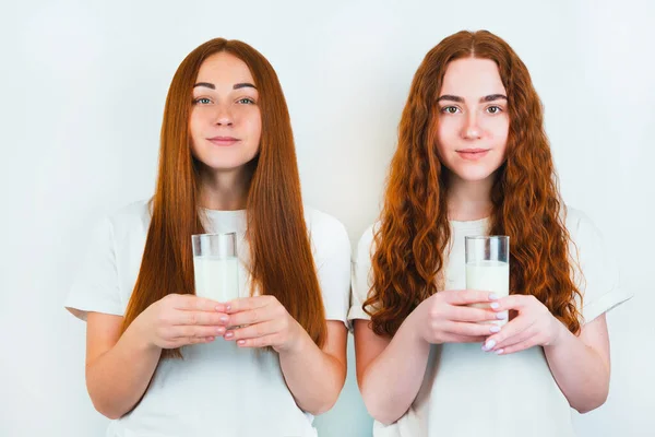 2人の赤毛の若い女性はどちらも乳を持っています隔離された白い背景に立っています健康的な食事のコンセプト — ストック写真