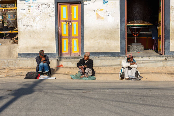 Three men sit on the road at the Swayambhunath temple