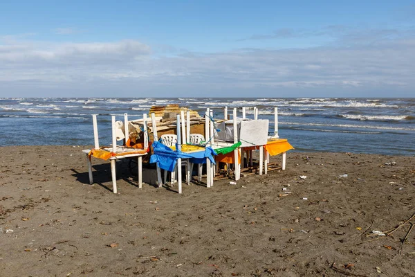 Пластиковые столы и стулья, сложенные на песчаном берегу перед бурей — стоковое фото