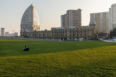 Heydar Aliyev Merkezi yakınlarındaki çimenlikte dinlenen genç bir adam var..