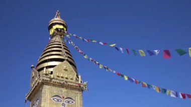 Eyes of the Buddha on the Swayambhunath stupa in Kathmandu. prayer flags in the wind