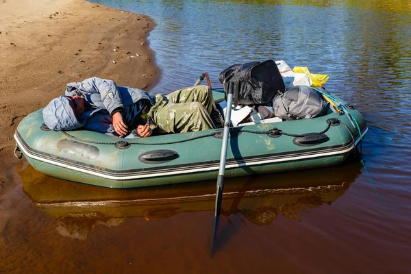 Balıkçı kıyıya yakın bir nehirde teknede uyur. — Stok fotoğraf