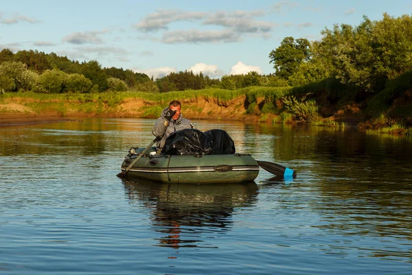 Un hombre flota en un bote de goma en el río Pizhma —  Fotos de Stock
