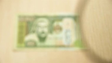 Masada elinde büyüteçle duran 500 Moğol Tugrik banknotuna bakın. iş ve finans kavramı.