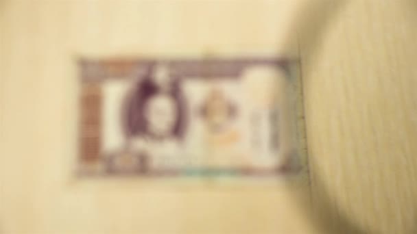 看一张100张蒙古包头巾的钞票躺在桌子上 桌子上放着放大镜 商业和金融的概念 — 图库视频影像