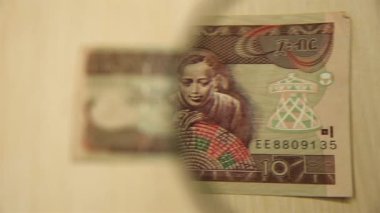 Masada elinde büyüteçle duran 10 Etiyopya Birr banknotuna bakın. iş ve finans kavramı.