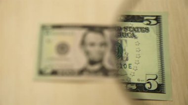Masada elinde büyüteçle duran beş dolarlık banknota bakın. iş ve finans kavramı