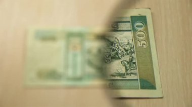 Masada elinde büyüteçle duran 500 Moğol Tugrik banknotuna bakın. İş ve finans kavramı. ters taraf