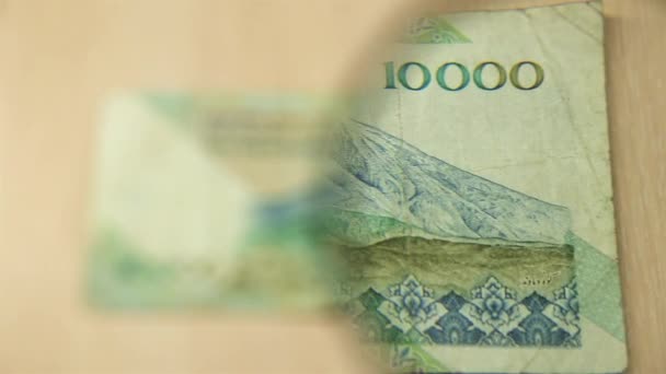 看一张1万伊朗里亚尔的钞票躺在桌子上 桌子上放着放大镜 商业和金融的概念 — 图库视频影像