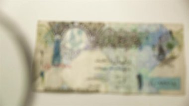 Bir Katar riyal ve bir büyüteç. Bir kağıt faturayı büyüteçten izle. ters.