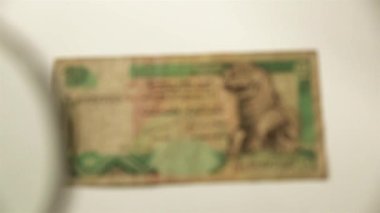 On Sri Lanka Rupisi ve büyüteç. Bir kağıt faturayı büyüteçten izle. Obverse.