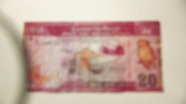 20 Sri Lanka Rupisi ve büyüteç. Bir kağıt faturayı büyüteçten izle. Obverse.