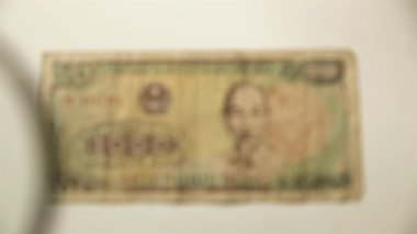 Bin Vietnamlı Dong ve bir büyüteç. Bir kağıt faturayı büyüteçten izle. Obverse.