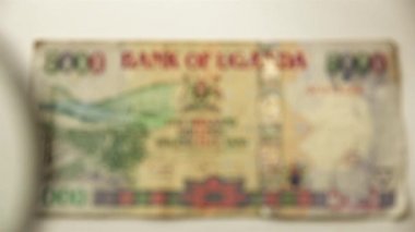 Beş bin Ugandalı şilin ve bir büyüteç. Bir kağıt faturayı büyüteçten izle. Obverse