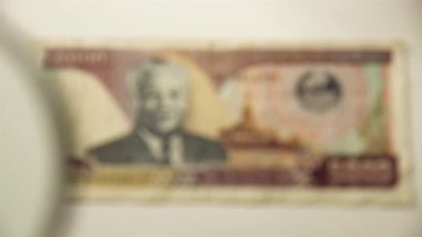 Beş bin Lao Kip ve bir büyüteç. Bir kağıt faturayı büyüteçten izle. Obverse.