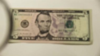 Beş Amerikan doları ve bir büyüteç. Bir kağıt faturayı büyüteçten izle. Obverse.