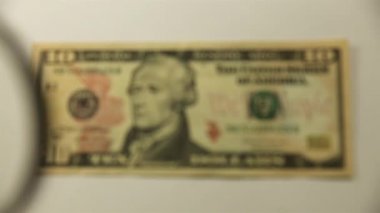 On Amerikan doları ve bir büyüteç. Bir kağıt faturayı büyüteçten izle. Obverse.