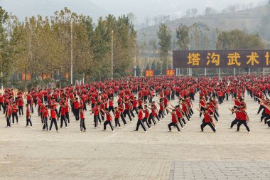 Dengfeng, Zhengzhou, Henan, Çin - 16 Ekim 2018: Shaolin Dövüş Sanatları Okulu. Dövüş sanatları öğrencilerinden oluşan büyük bir grup meydanda eğitim görüyor..