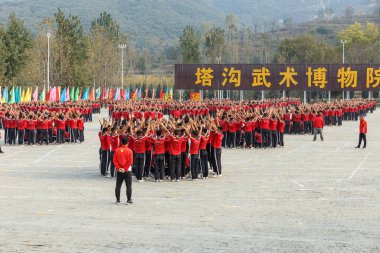 Dengfeng, Zhengzhou, Henan, Çin - 17 Ekim 2018: Shaolin Dövüş Sanatları Okulu. Dövüş sanatları öğrencilerinden oluşan büyük bir grup meydanda eğitim görüyor..