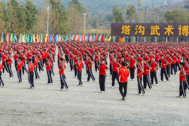 Dengfeng, Zhengzhou, Henan, Çin - 17 Ekim 2018: Shaolin Dövüş Sanatları Okulu. Dövüş sanatları öğrencilerinden oluşan büyük bir grup meydanda eğitim görüyor..
