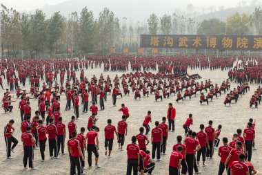 Dengfeng, Zhengzhou, Henan, Çin - 17 Ekim 2018: Shaolin Dövüş Sanatları Okulu. Dövüş sanatları öğrencilerinden oluşan büyük bir grup meydanda eğitim görüyor..