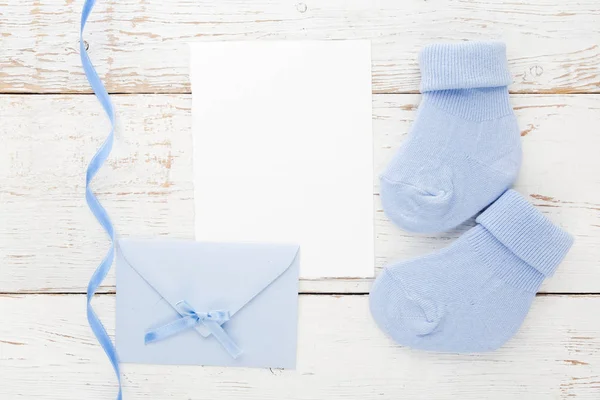 Small boy blue socks, blank card and evelop on white wooden background. Flat lay. — Stock Photo, Image