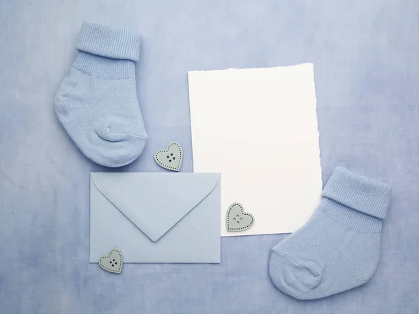 Маленькие носки мальчика, пустая карточка и evelop на синем фоне ткани. Плоский лежал . — стоковое фото
