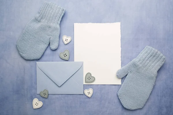 Guantes de bebé pequeños, tarjeta en blanco y evelop sobre fondo de tela azul. Acostado. Vista superior — Foto de Stock