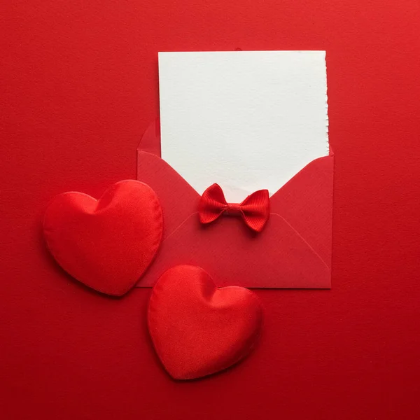 Envolvente de correo, corazón y cinta sobre fondo rojo. Tarjeta de San Valentín, Amor o Boda Concepto de Saludo. Vista superior —  Fotos de Stock