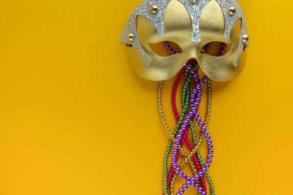 Маска Марис Гра и бусы на желтом фоне с копировальным пространством
