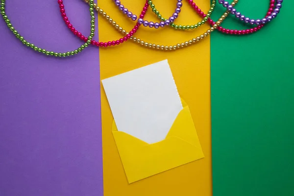 Multi Barva Mardi Gras korálky a obklopit s kartou na pozadí papíru. Pohled shora — Stock fotografie
