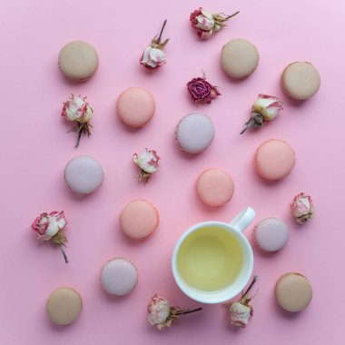 Fransız tatlı macarons pembe bir arka plan üzerinde kuru gül çiçek desenle. Düz yatıyordu