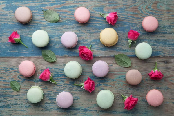 Macarons flat lay withroses and leaves on green wooden background. Top view — Stock Photo, Image