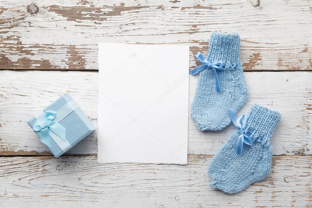 beautiful gift, babys socks and blank postcard on white wooden background. Flat lay