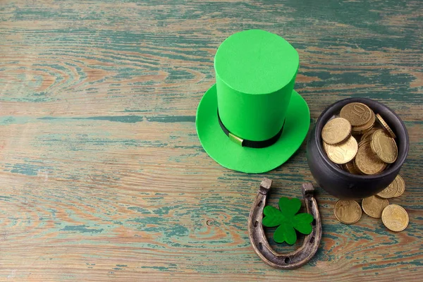 Feliz día de San Patricio sombrero duende con monedas de oro y amuletos de la suerte sobre fondo de madera verde estilo vintage. Vista superior — Foto de Stock