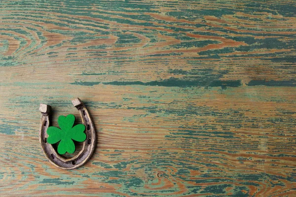 Dia de St. Patricks, amuletos da sorte. Horesechoe e trevo sobre fundo de madeira — Fotografia de Stock