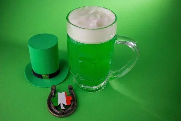 St Patricks Day grön öl med shamrock, hästsko och Leprechaun hat mot grön bakgrund. — Stockfoto