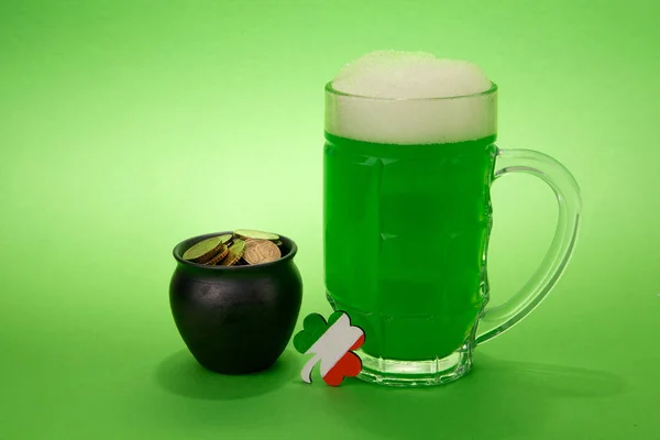 Día de San Patricio cerveza verde con trébol, olla con monedas de oro sobre fondo verde . — Foto de Stock