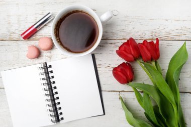 Kırmızı lale, kahve fincanı ve defter Beyaz ahşap masa üzerinde. Düz yatıyordu