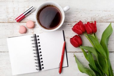 Kırmızı lale, kahve fincanı ve defter Beyaz ahşap masa üzerinde. Düz yatıyordu
